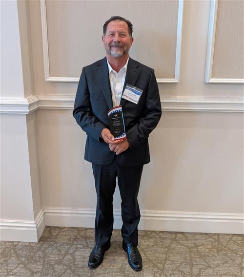 A man stands holding an award
